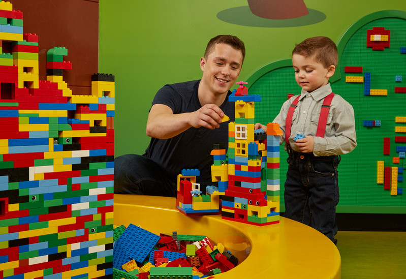 Father and son playing with legos in the animal-themed DUPLO® Farm area