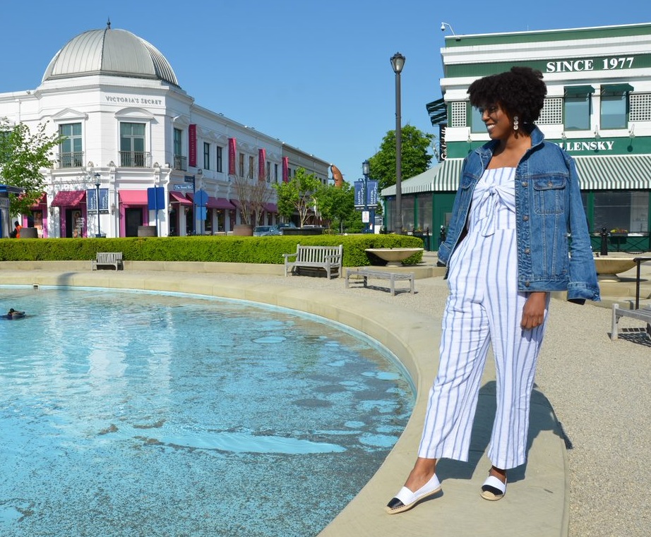 Woman in fashionable outfit standing by water pool at Easton with shops in background