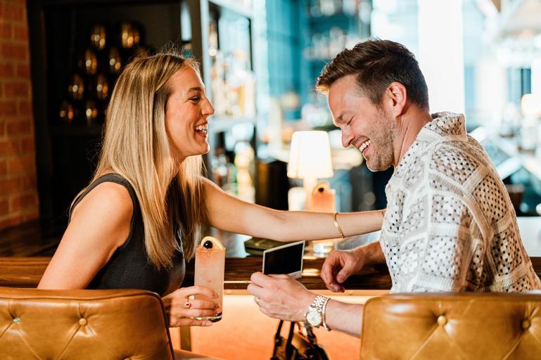 Man and woman laughing over drinks at Little West Tavern