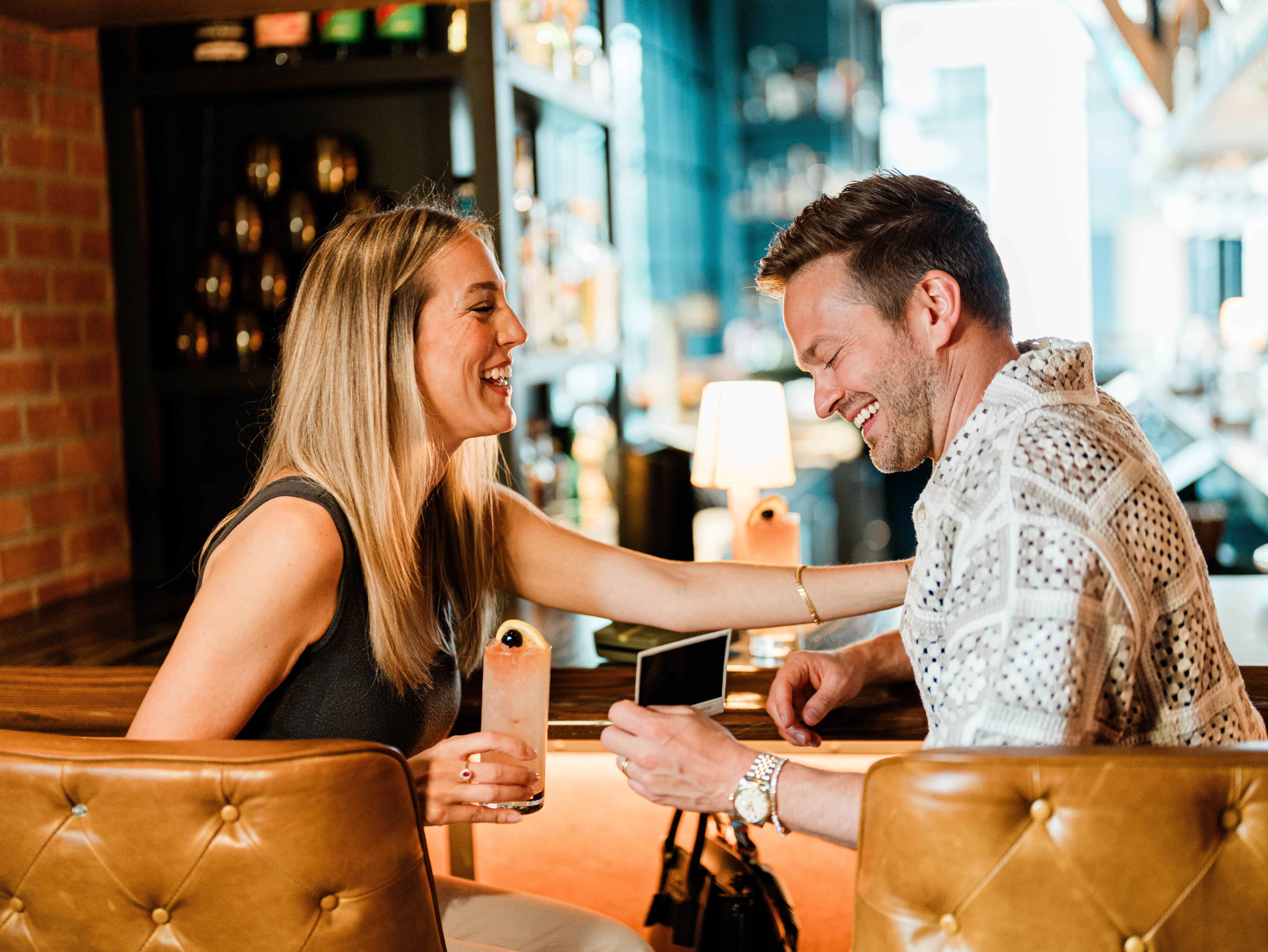 Man and woman laughing over drinks at Little West Tavern