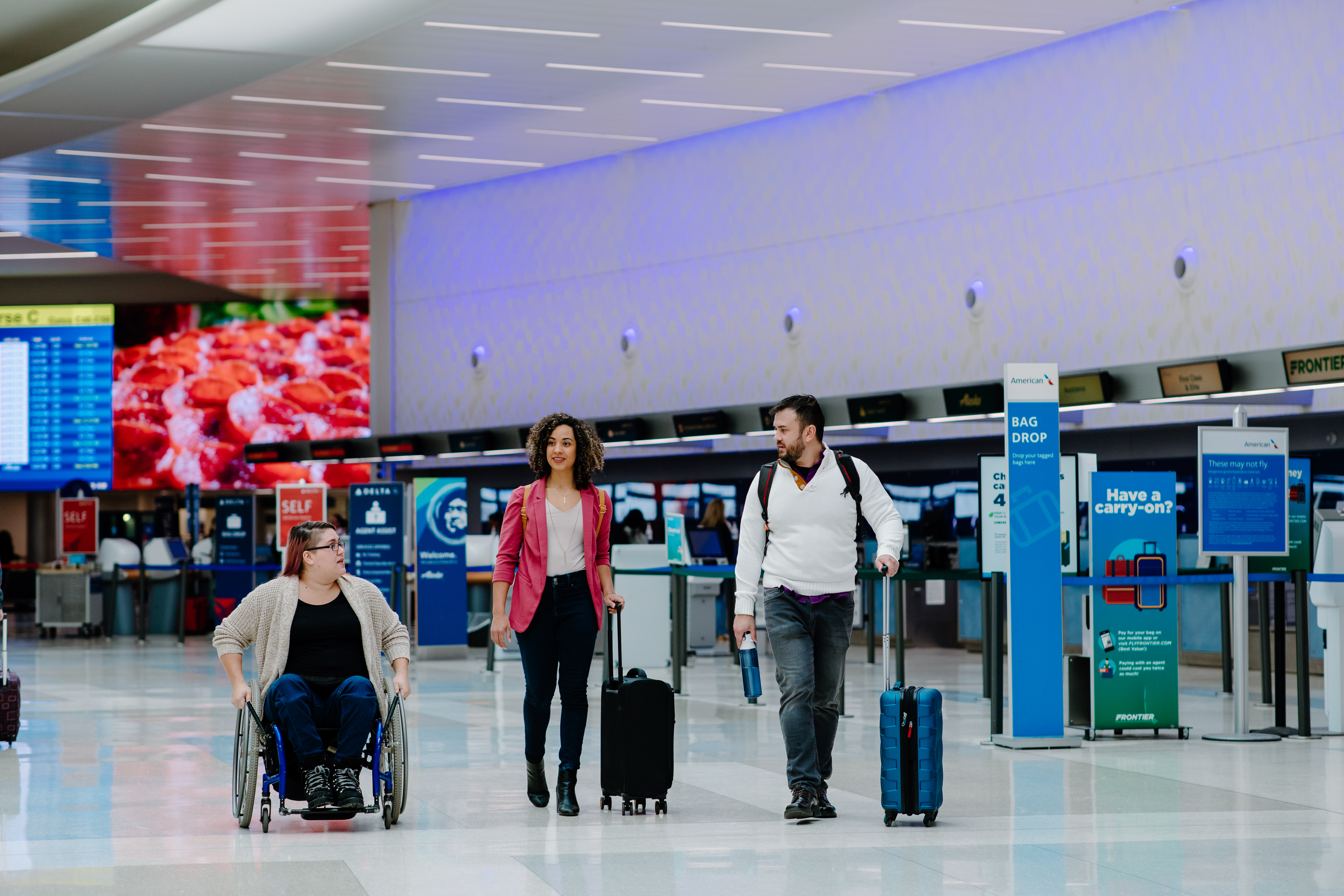 Two women and man entering John Glenn International Airport with luggage