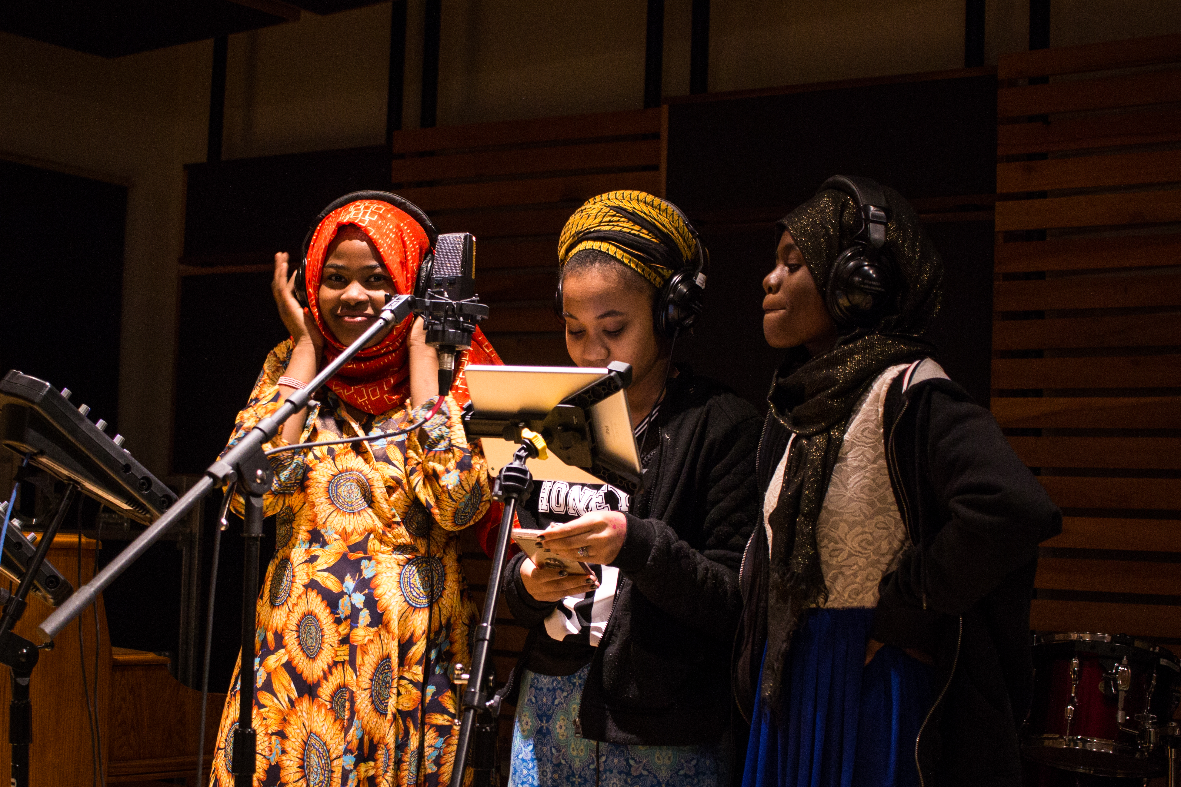 Diverse students standing at microphone in recording studio as a part of the We Amplify Voices program