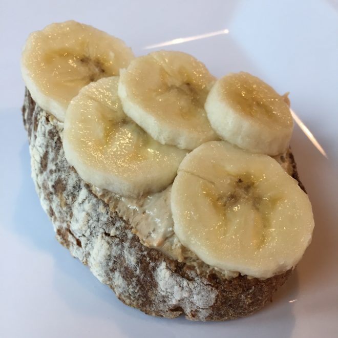 Slice of toast topped with banana on plate from Zest Juice