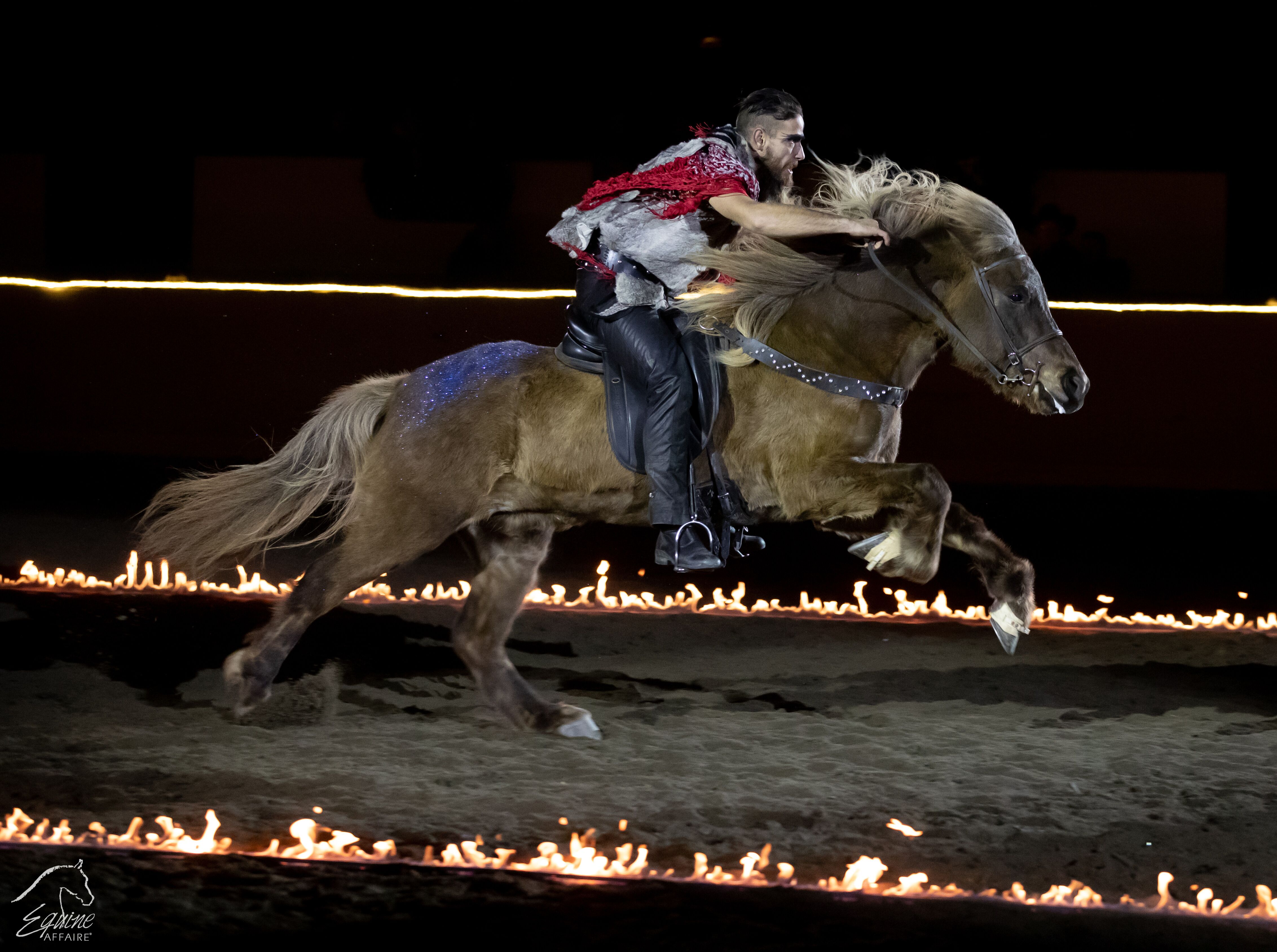 Man in cowboy costume on horseback galloping through flames at Equine Affaire's Fantasia event