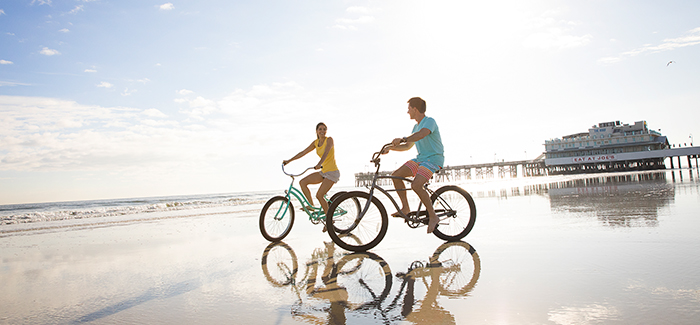 A couple enjoys bicycling on Daytona Beach near the Main Street Pier
