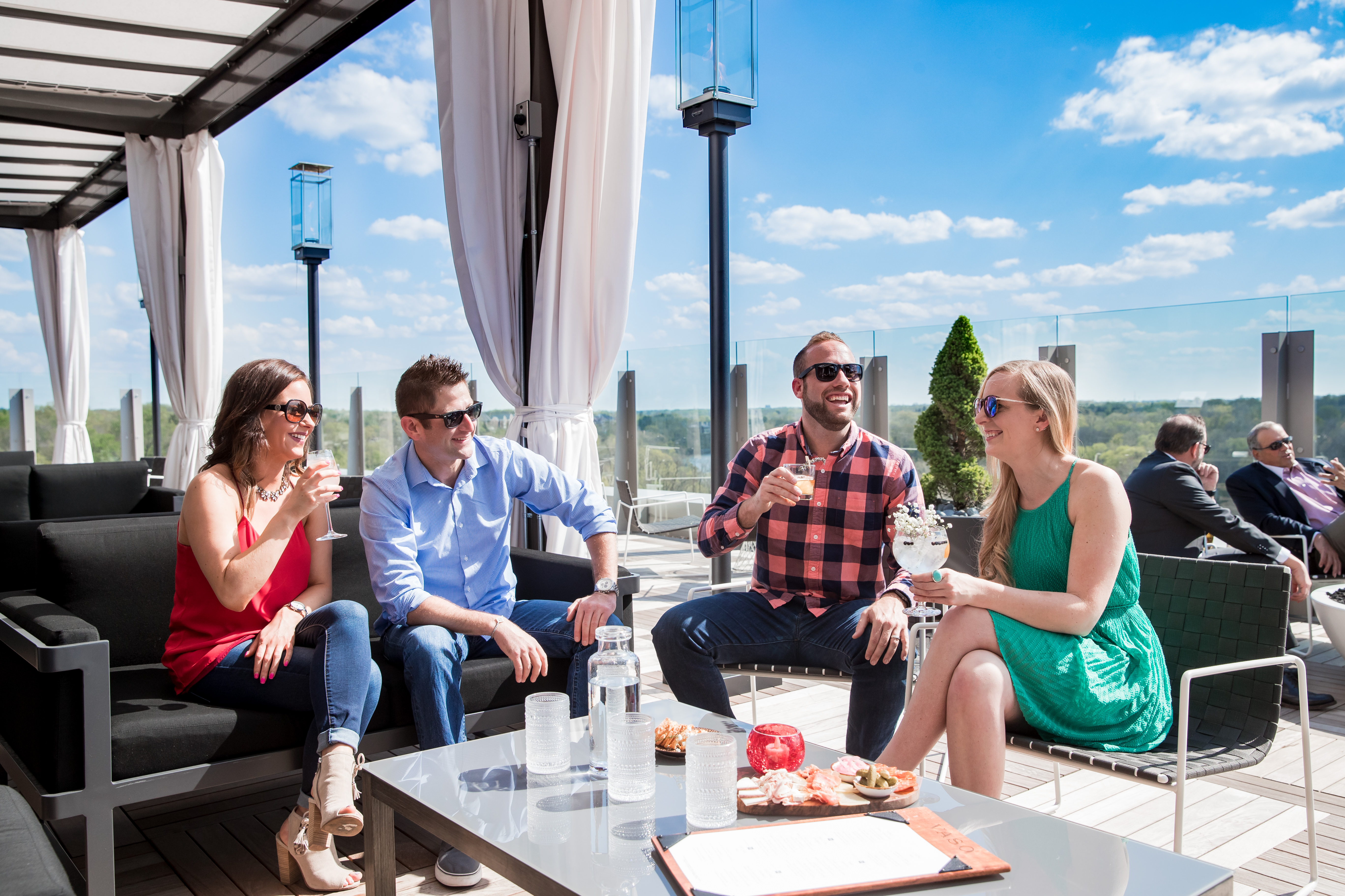 Two couples enjoying cocktails on the rooftop patio at VASO
