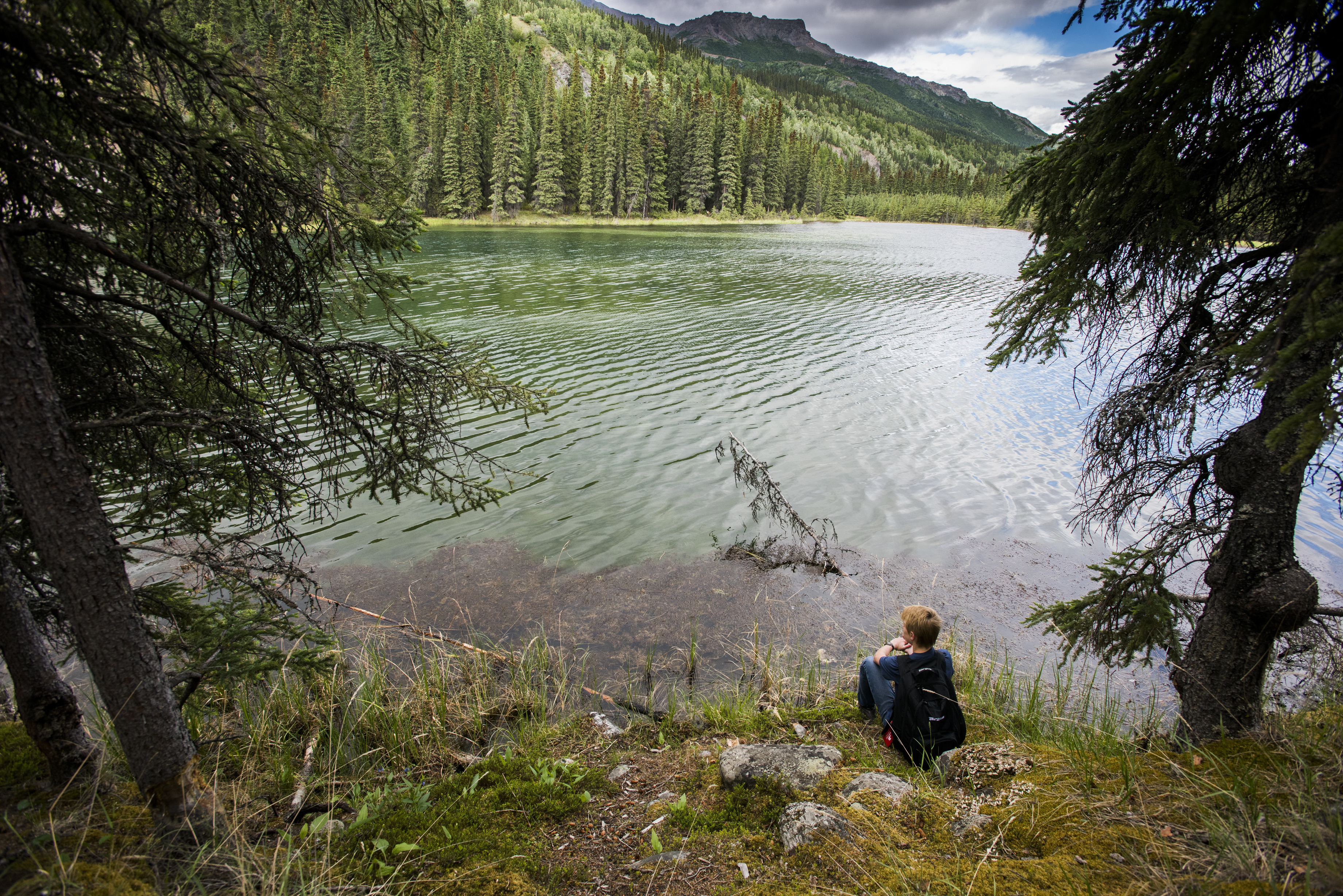 hiker sitting by a clear mountain lake