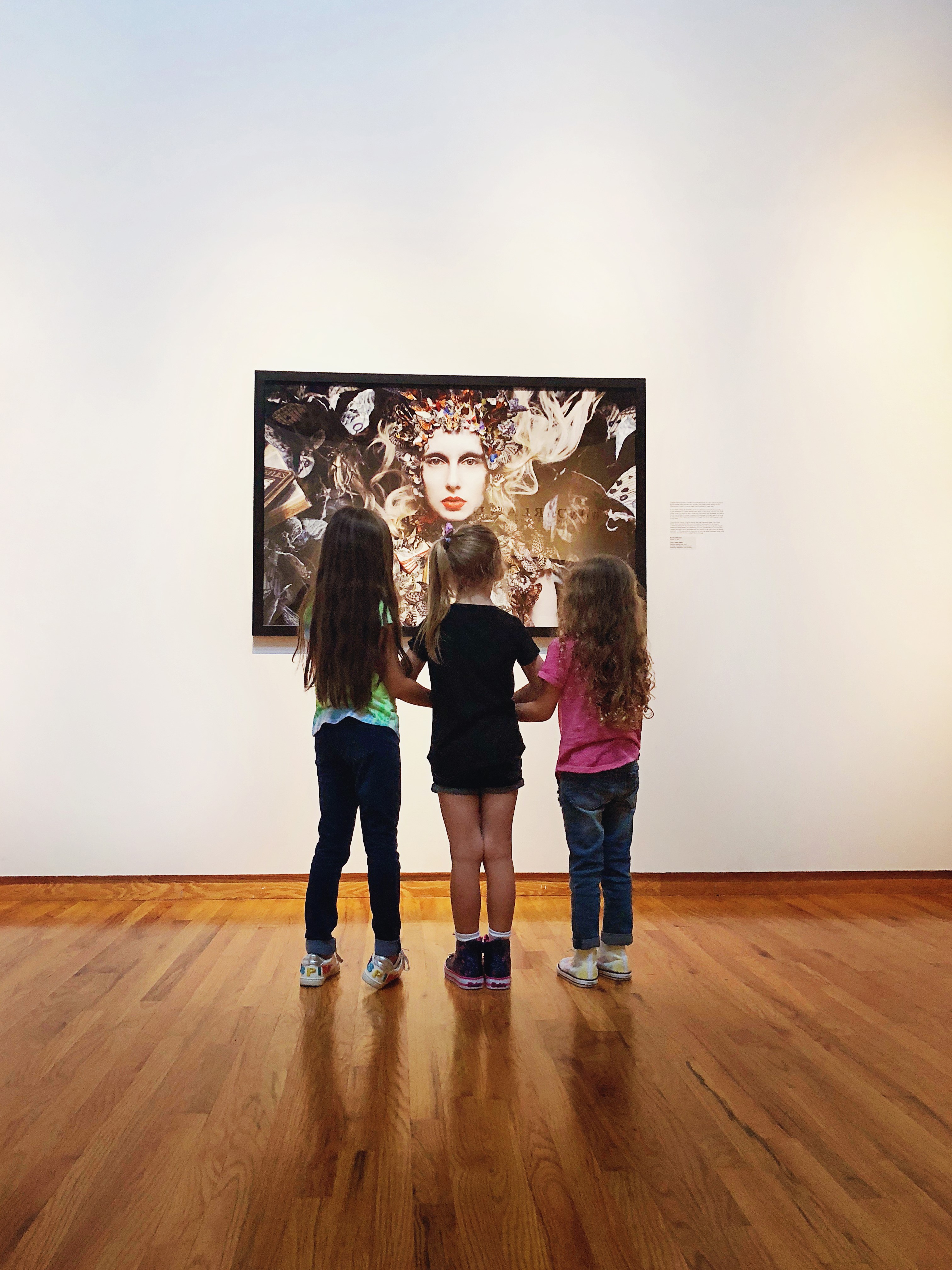 Three young girls browsing photography at the Fort Wayne Museum of Art