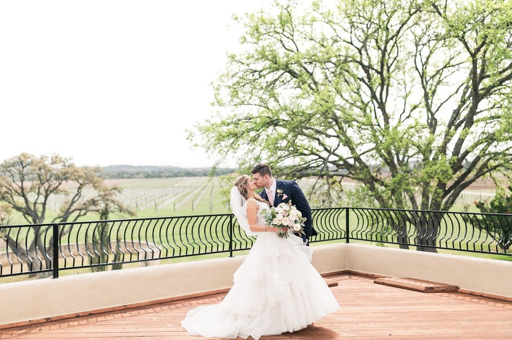 Bride and groom kissing with a view of the Texas Hill Country behind them