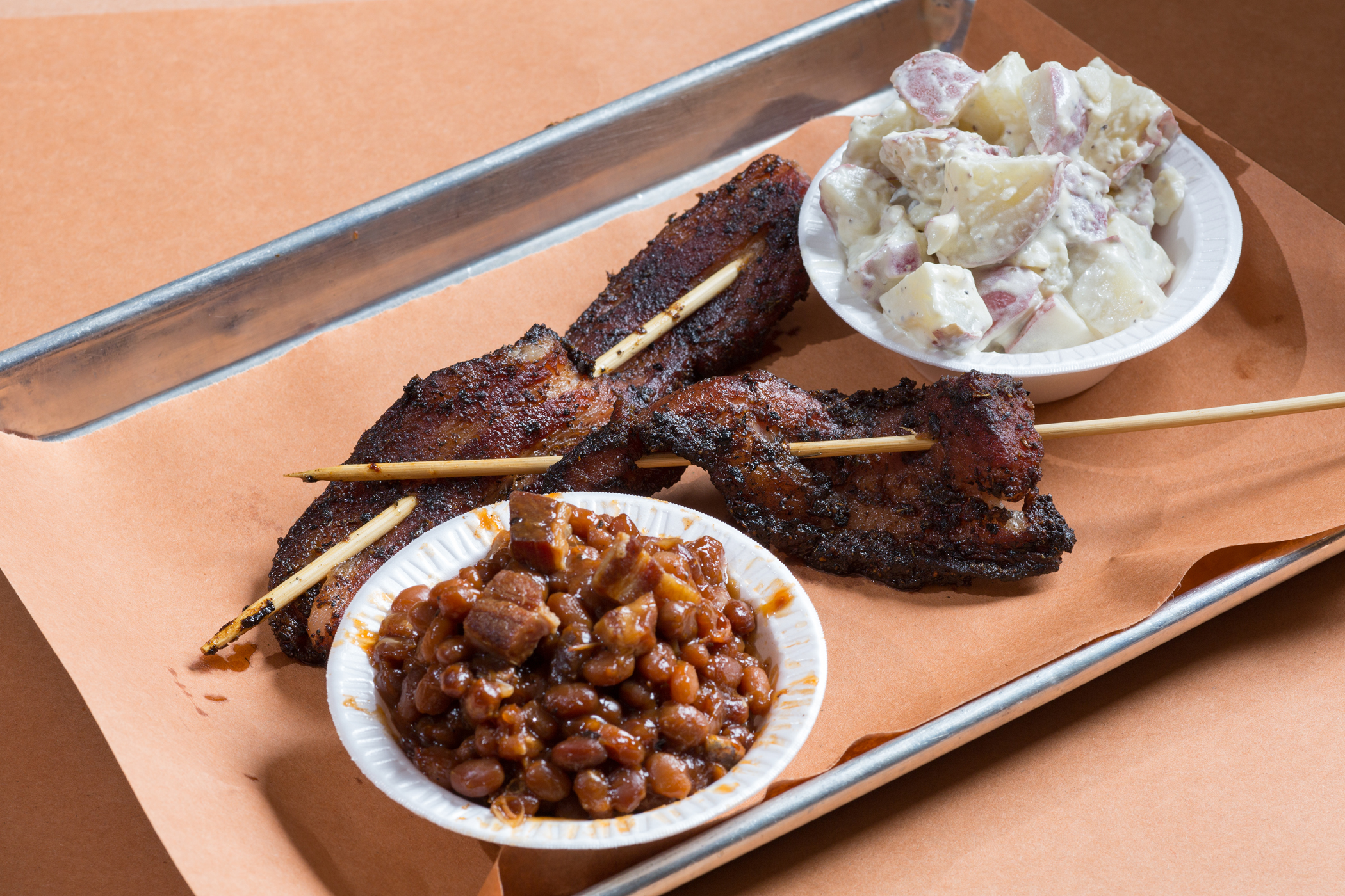 Monk's bacon on a stick with a side of baked beans and potato salad