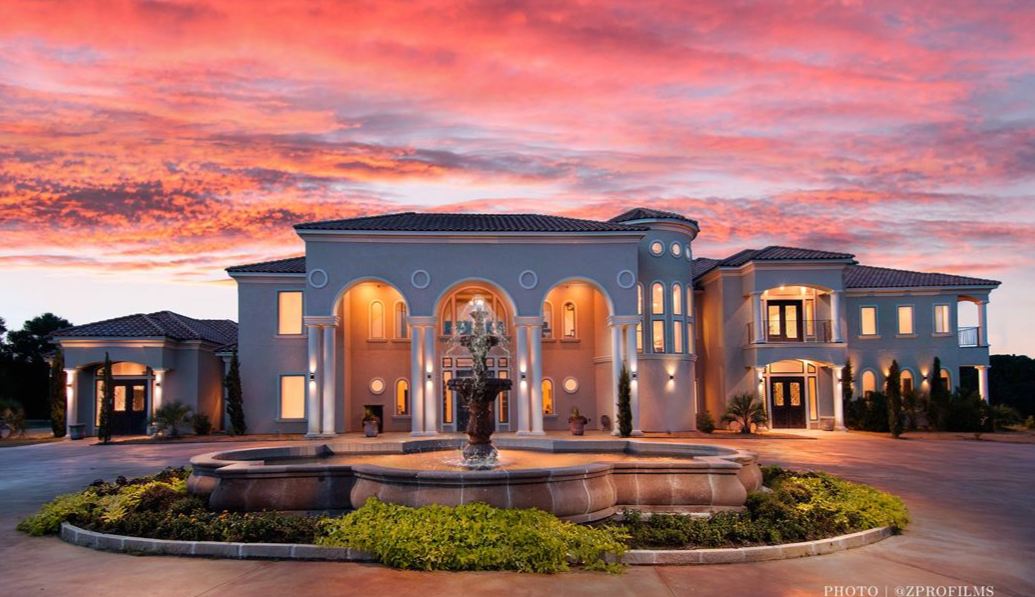 Castle-looing venue with a large fountain and colorful pink and blue sky.