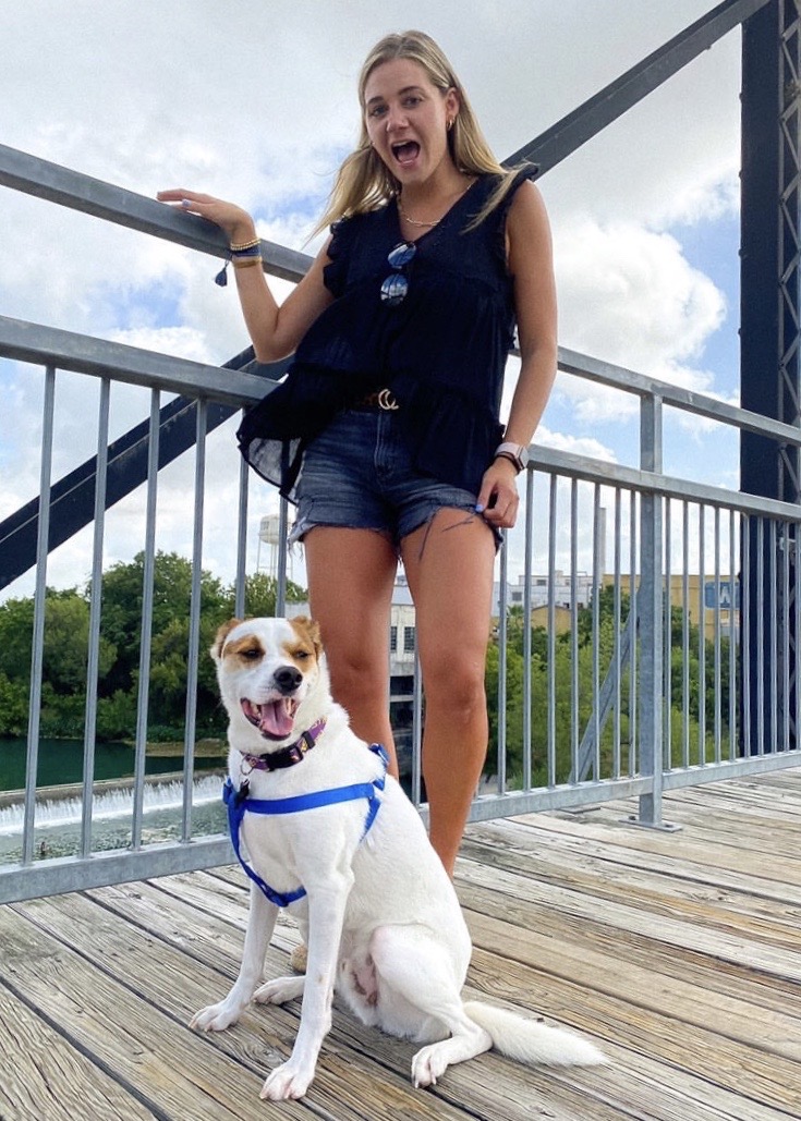 A young woman and her dog pose for a photo overlooking the river on the Faust Street Bridge in New Braunfels, Texas.