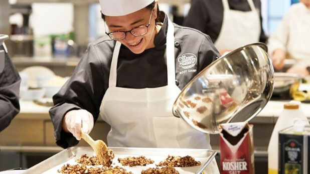 A student at Culinary Institute of America spoons ingredients onto a tray.