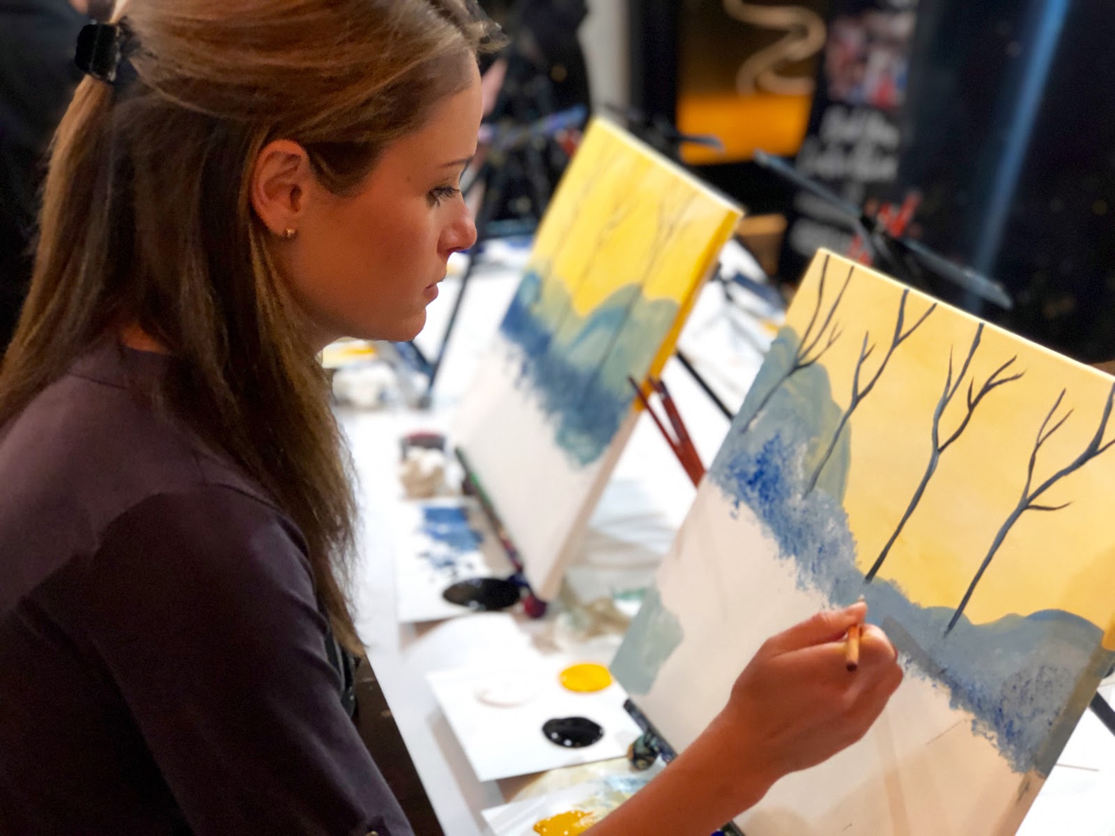 Woman in painting class working on canvas