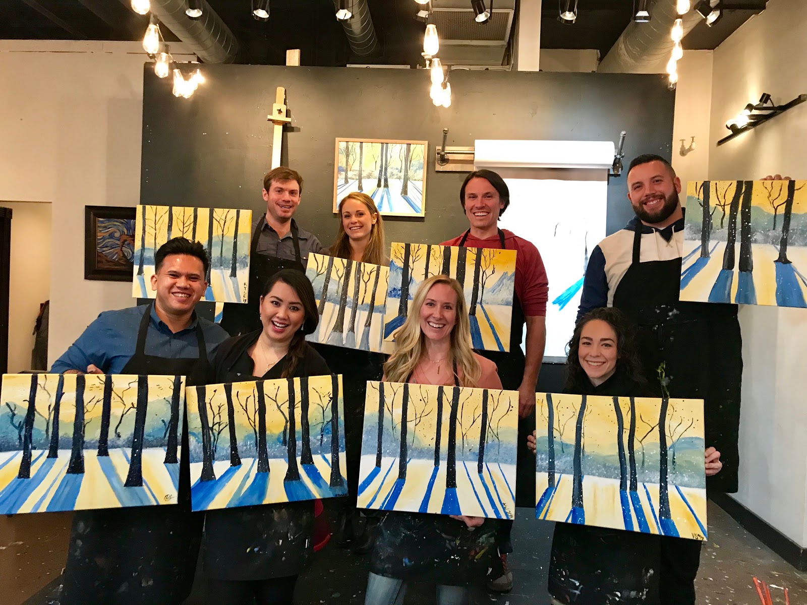 Group of adults holding finished painting after paint mixer class