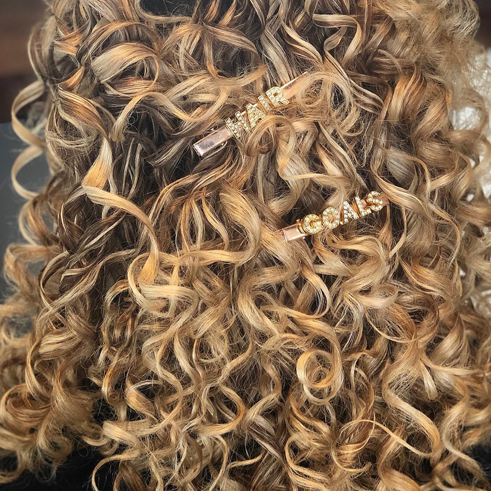 A head full of curls with pins reading Hair Goals