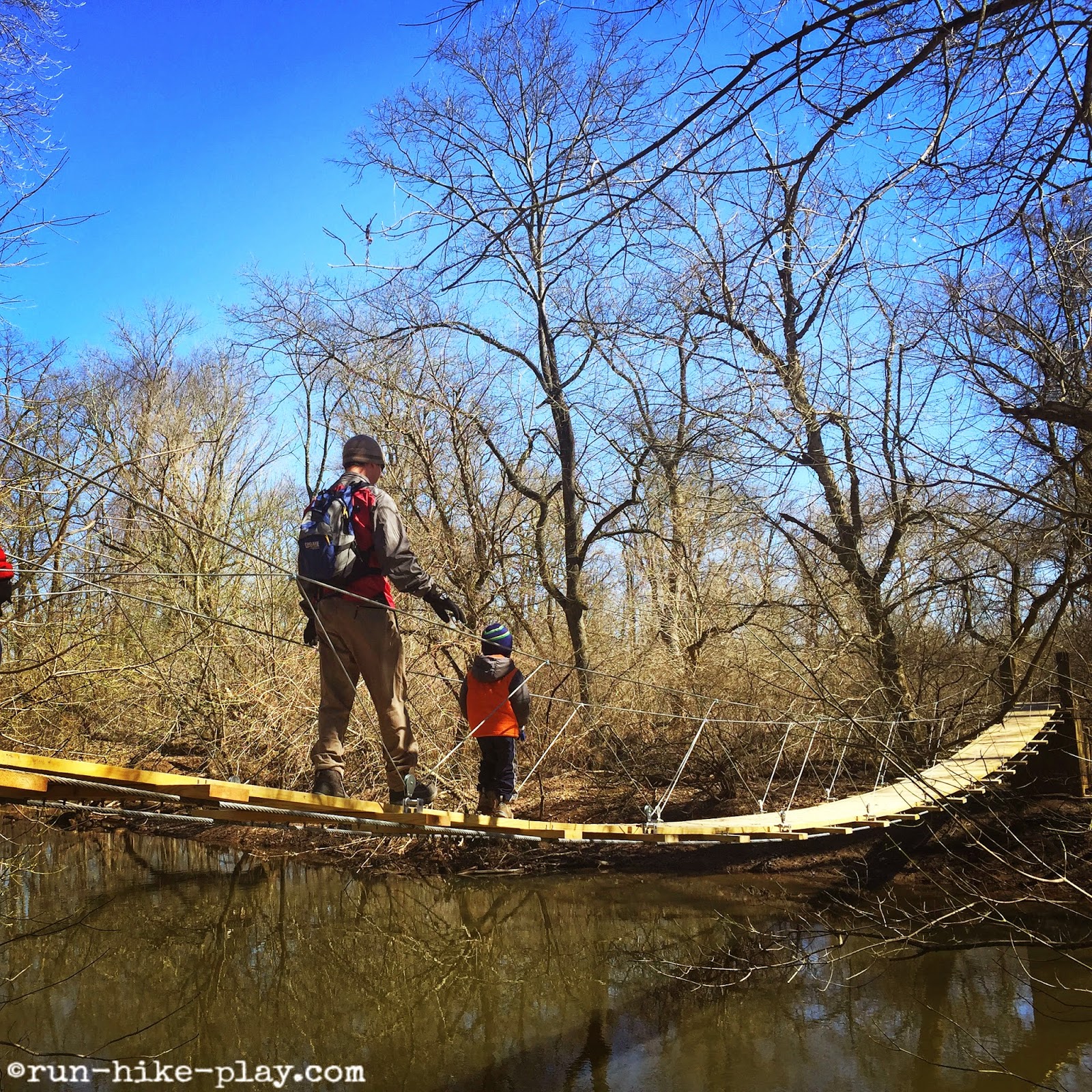 An adult and a child crossing over a rope bridge in Princeton Institute Woods
