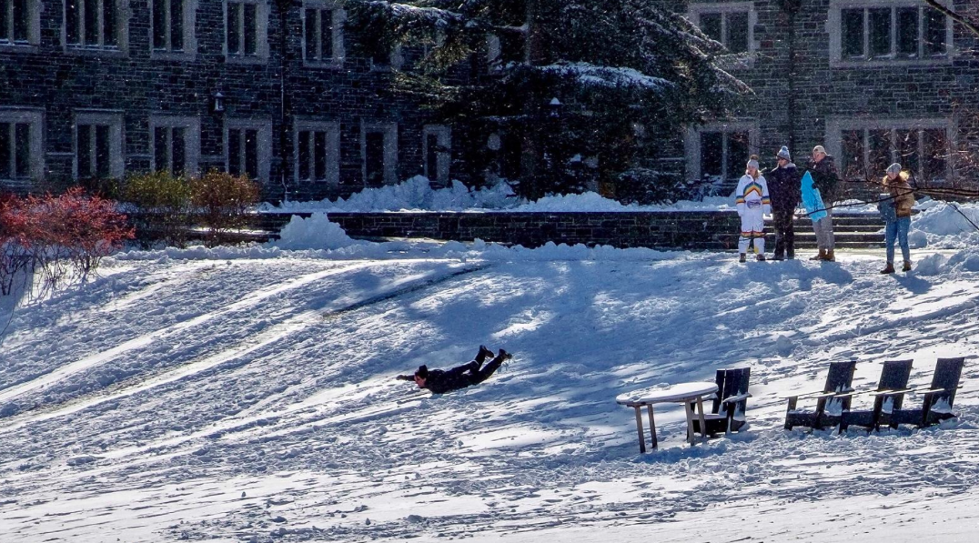A child sleds down a small hill on the campus of Princeton University