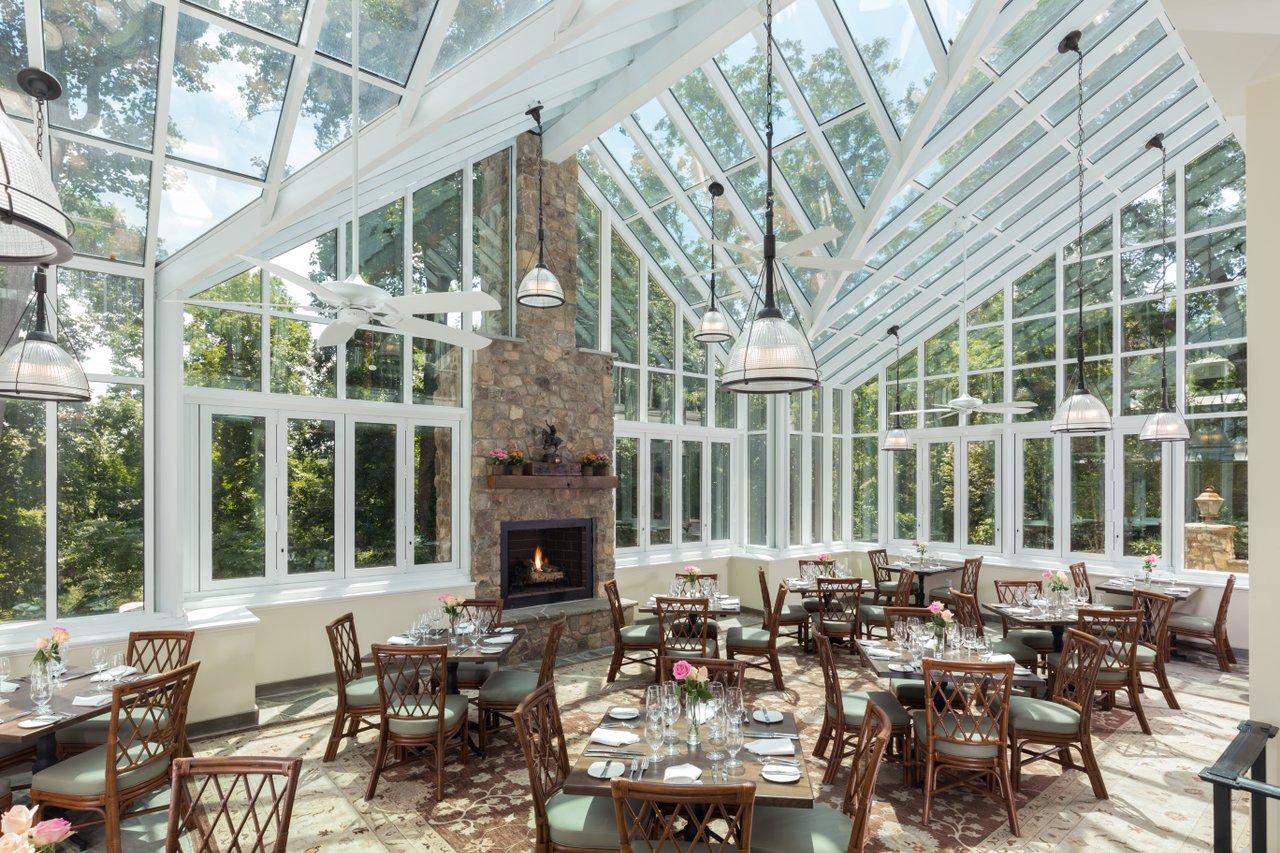Dining tables and fireplace in the glass-walled conservatory at Goodstone Inn & Restaurant
