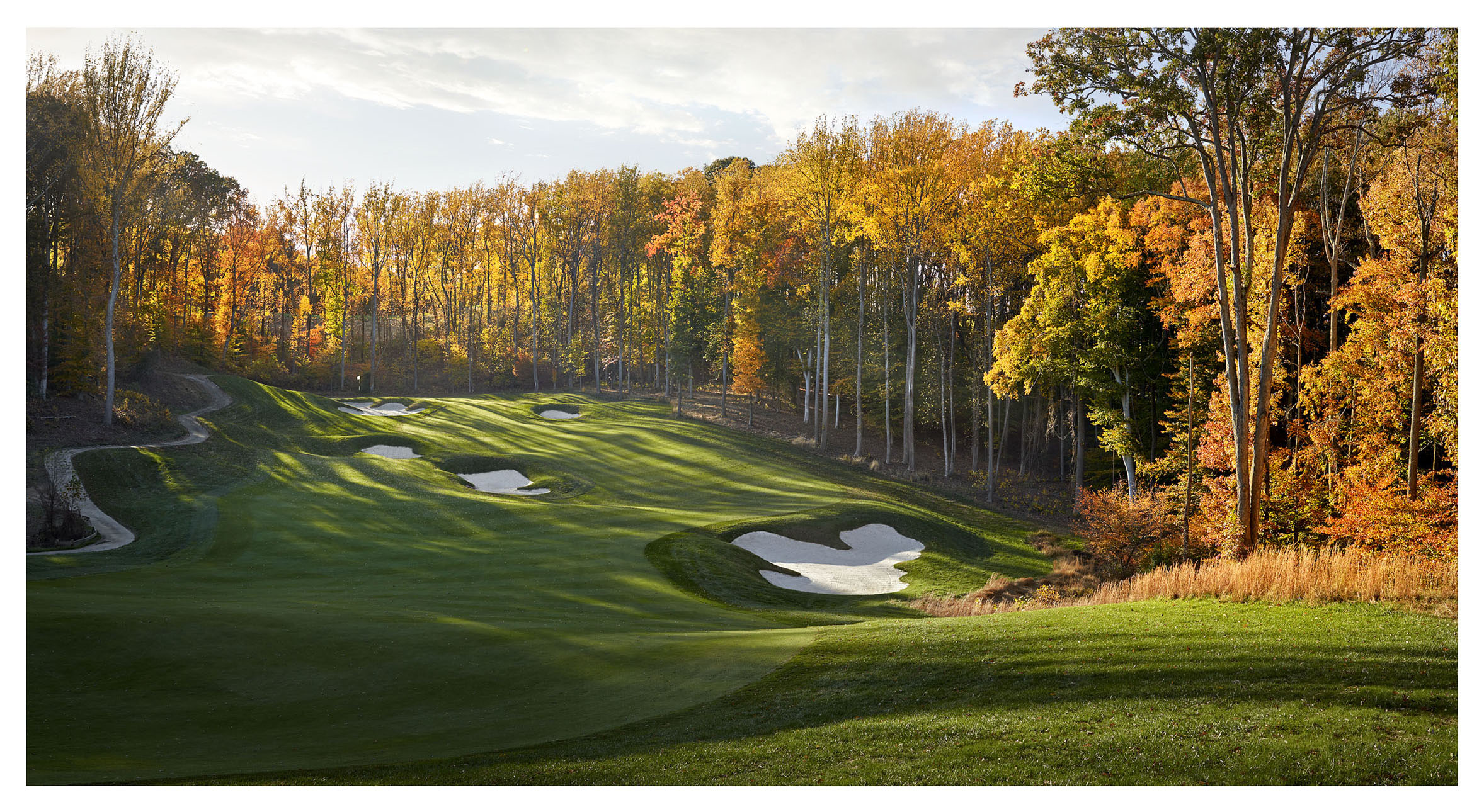 A golf course surrounded by trees with fall foliage