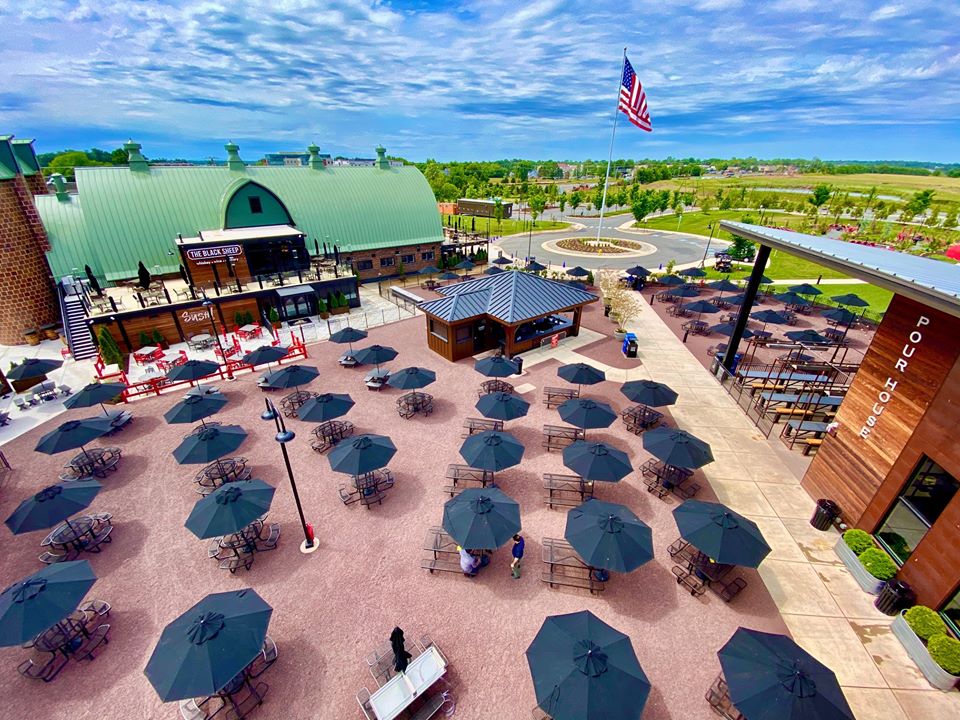 Aerial shot of Farm Brew Live Campus with social distancing of tables with black umbrellas spaced out.