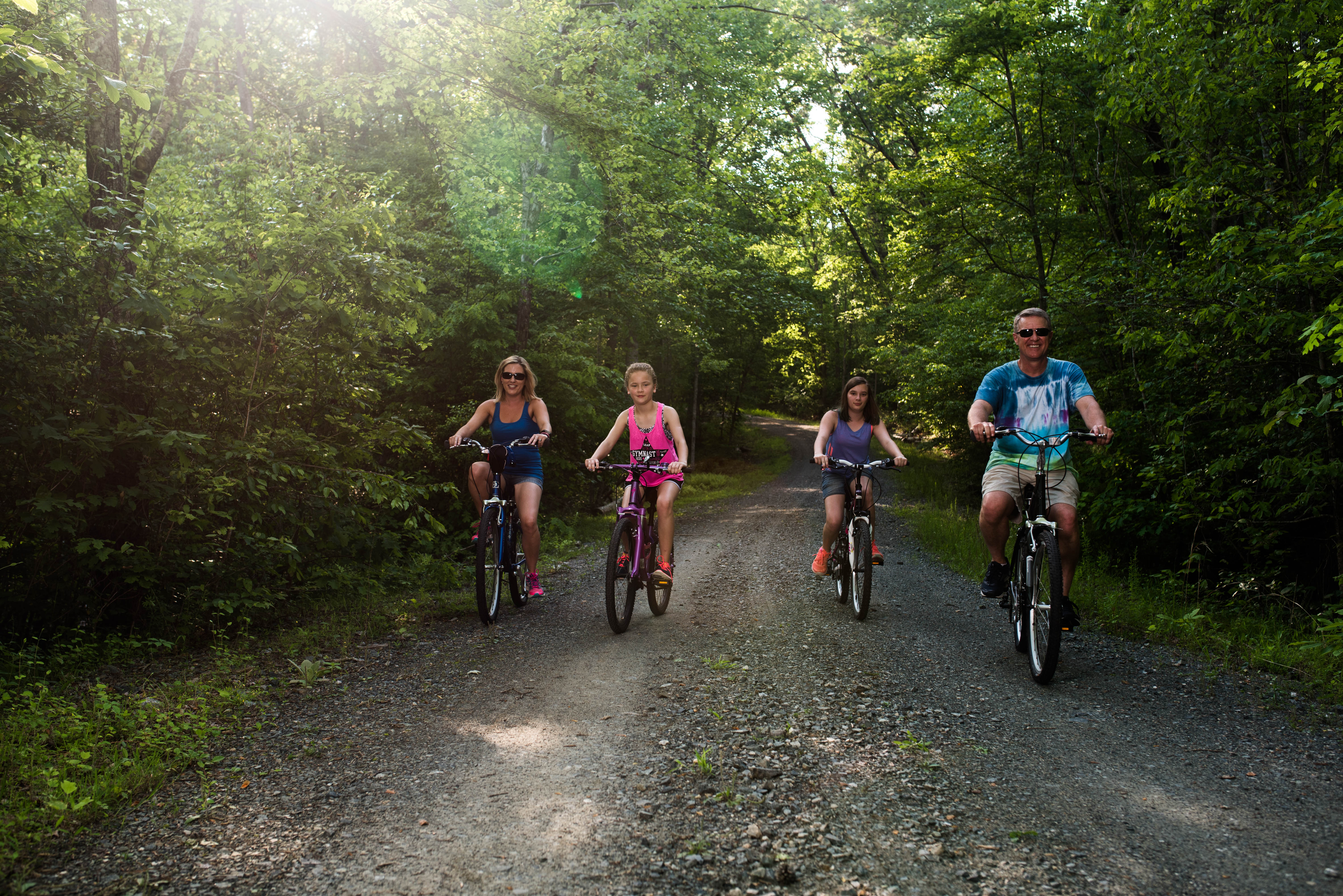 A family riding their bikes on a path in the forest