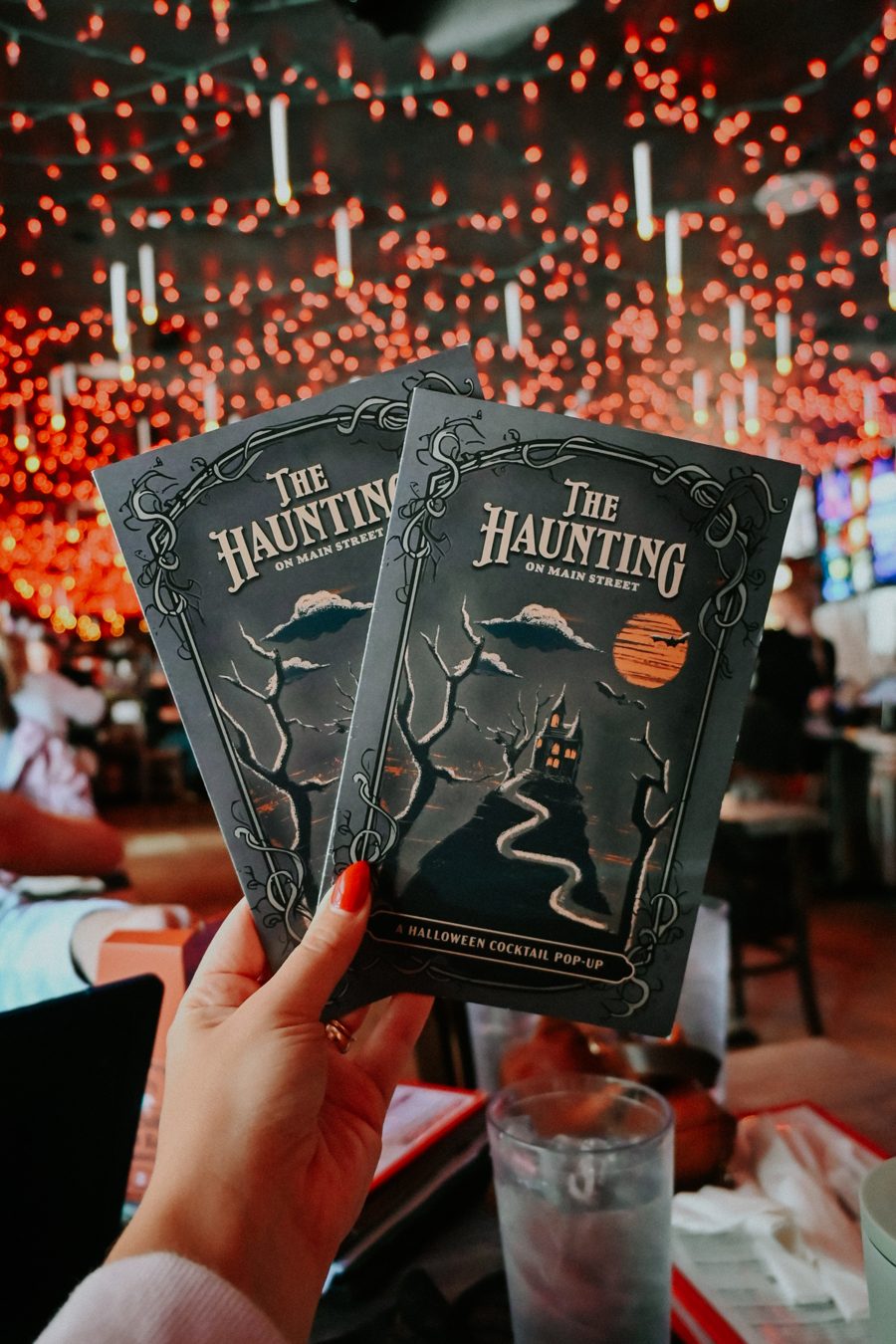 The Haunting cocktail menus beneath glowing Halloween decorations