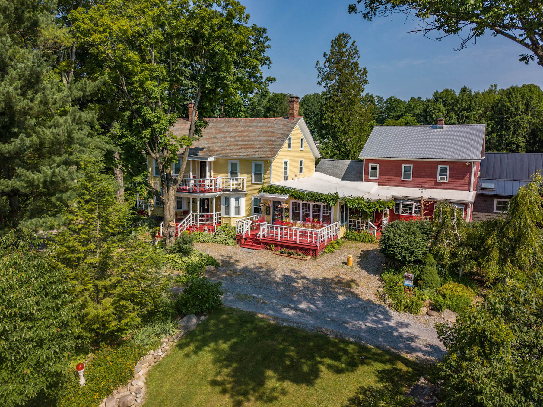 Exterior shot of yellow and red Saratoga Farmstead Bed & Breakfast with luscious greenery