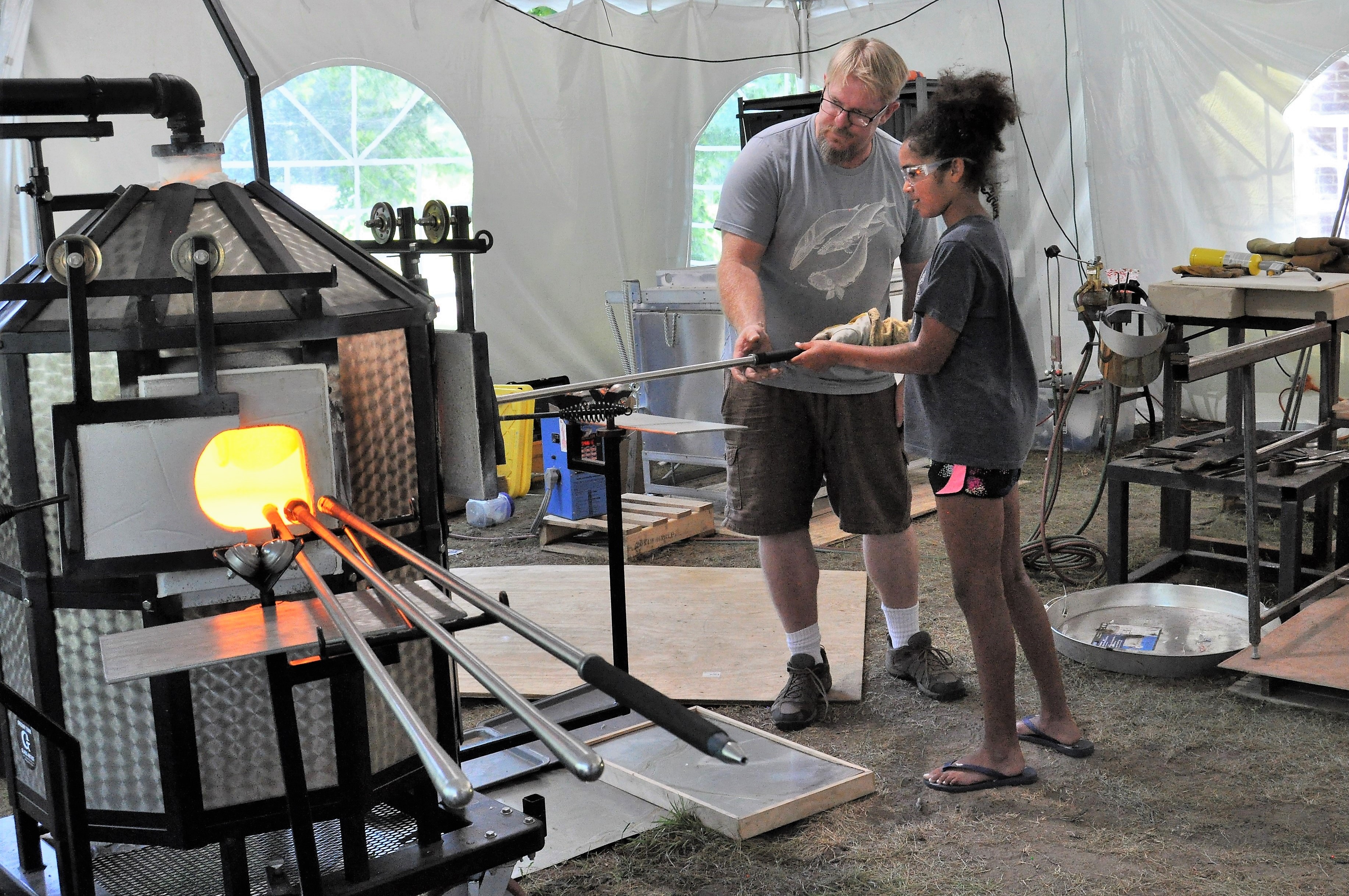 Greg helping his young student put her project in the furnace