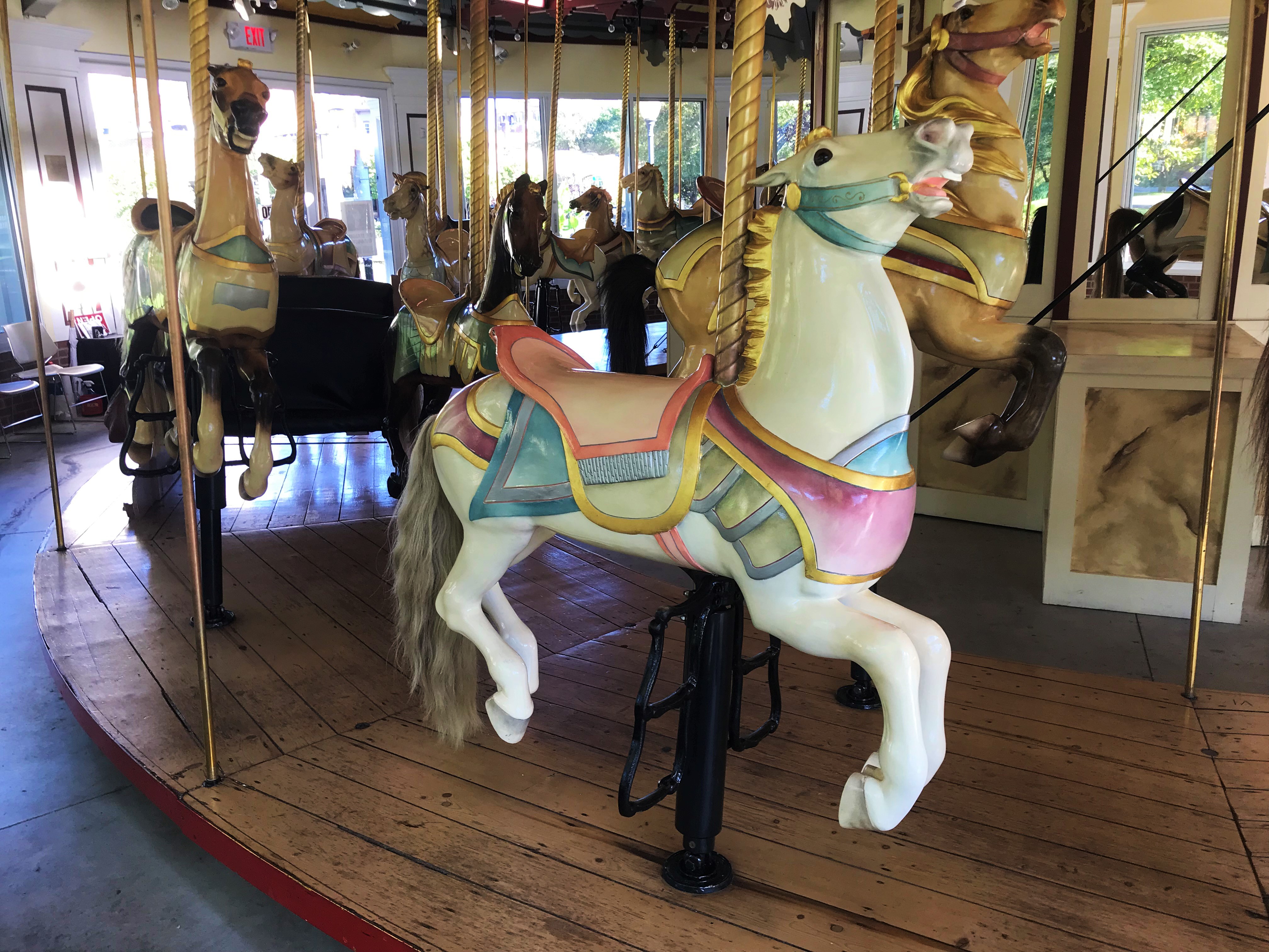 Closeup of a white carousel horse with pink saddle