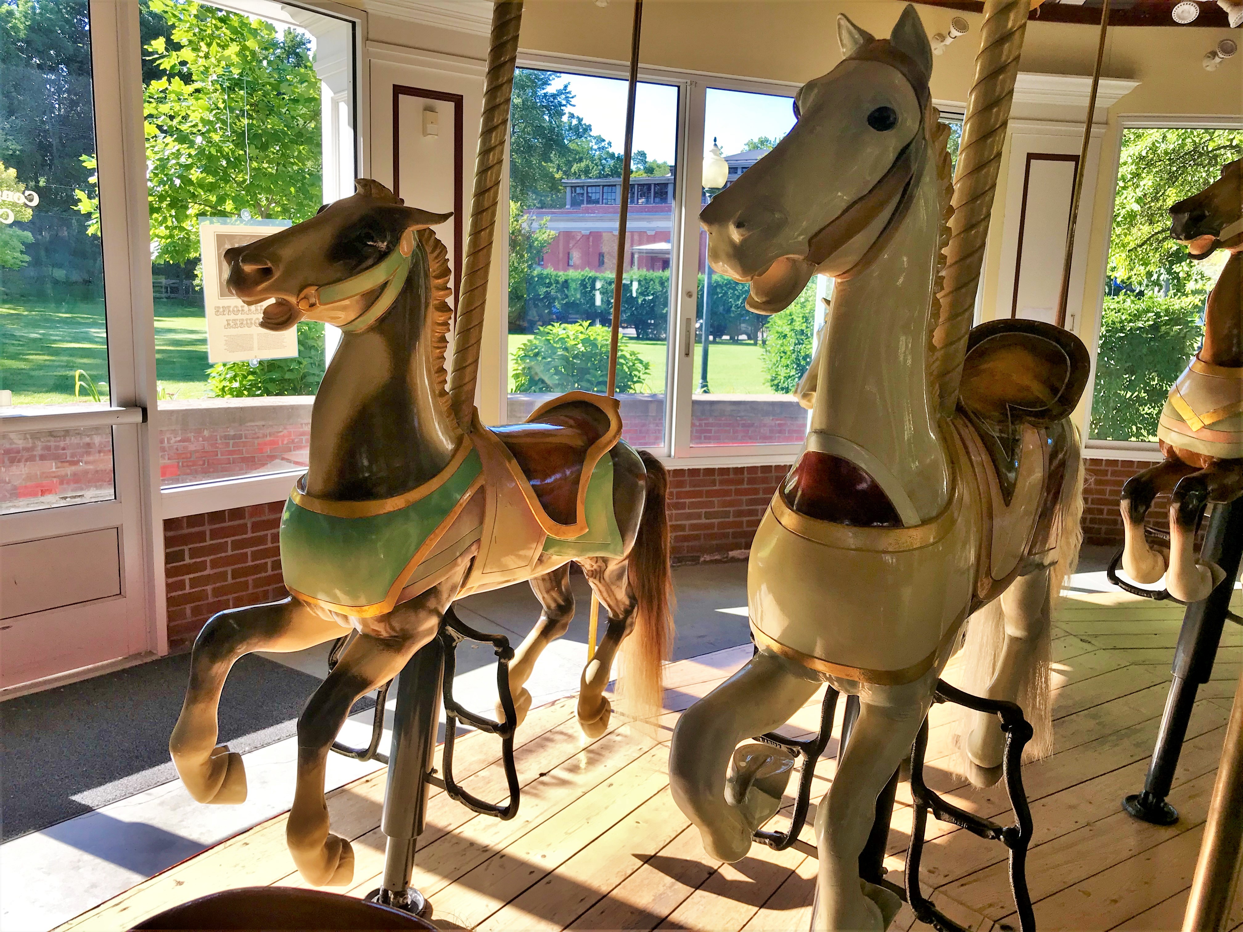 Two carousel horses side by side in the sunlight