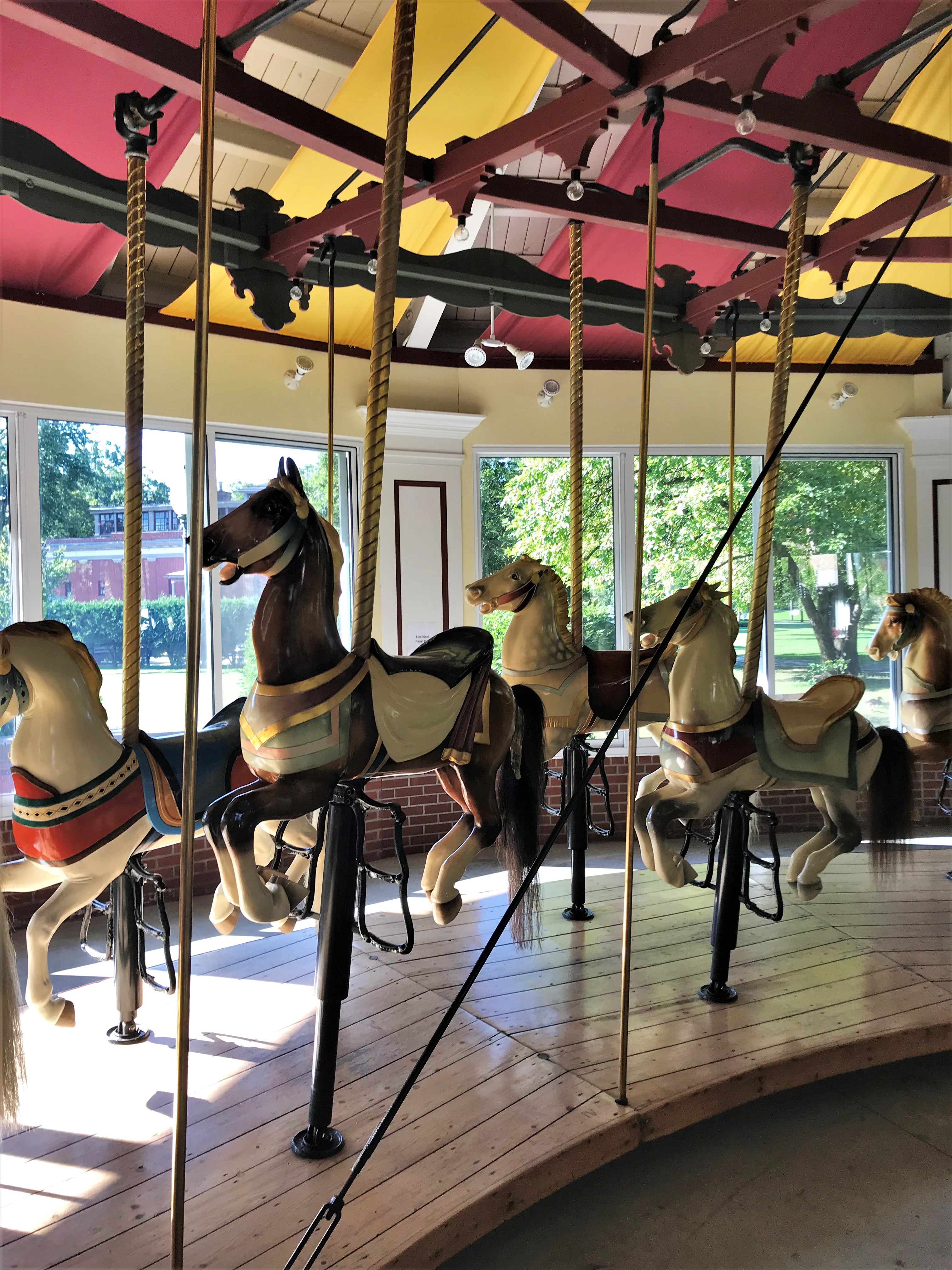 Several carousel horses with red and yellow ceiling