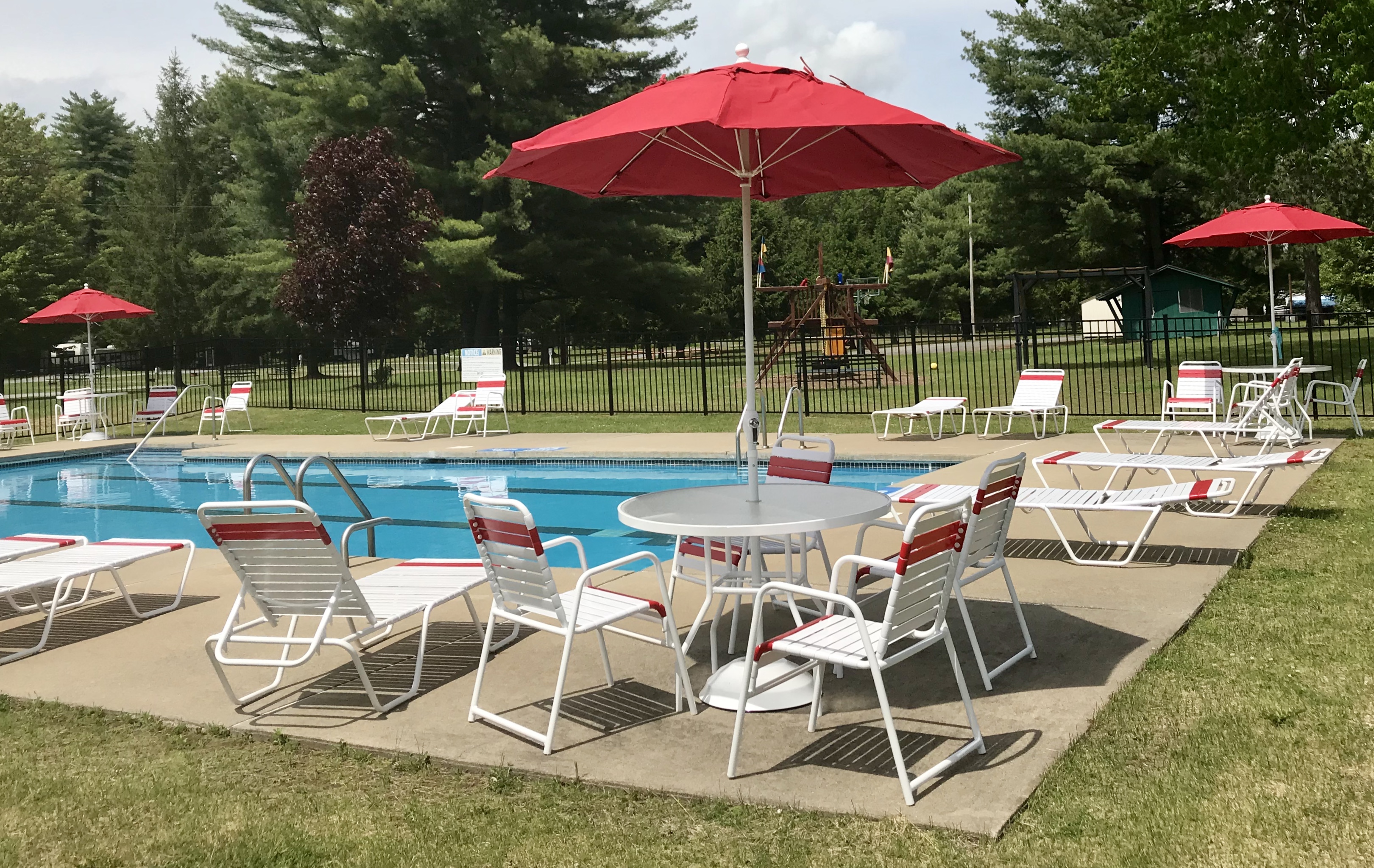 Saratoga RV Park pool and patio area with table amd red umbrellas around the pool