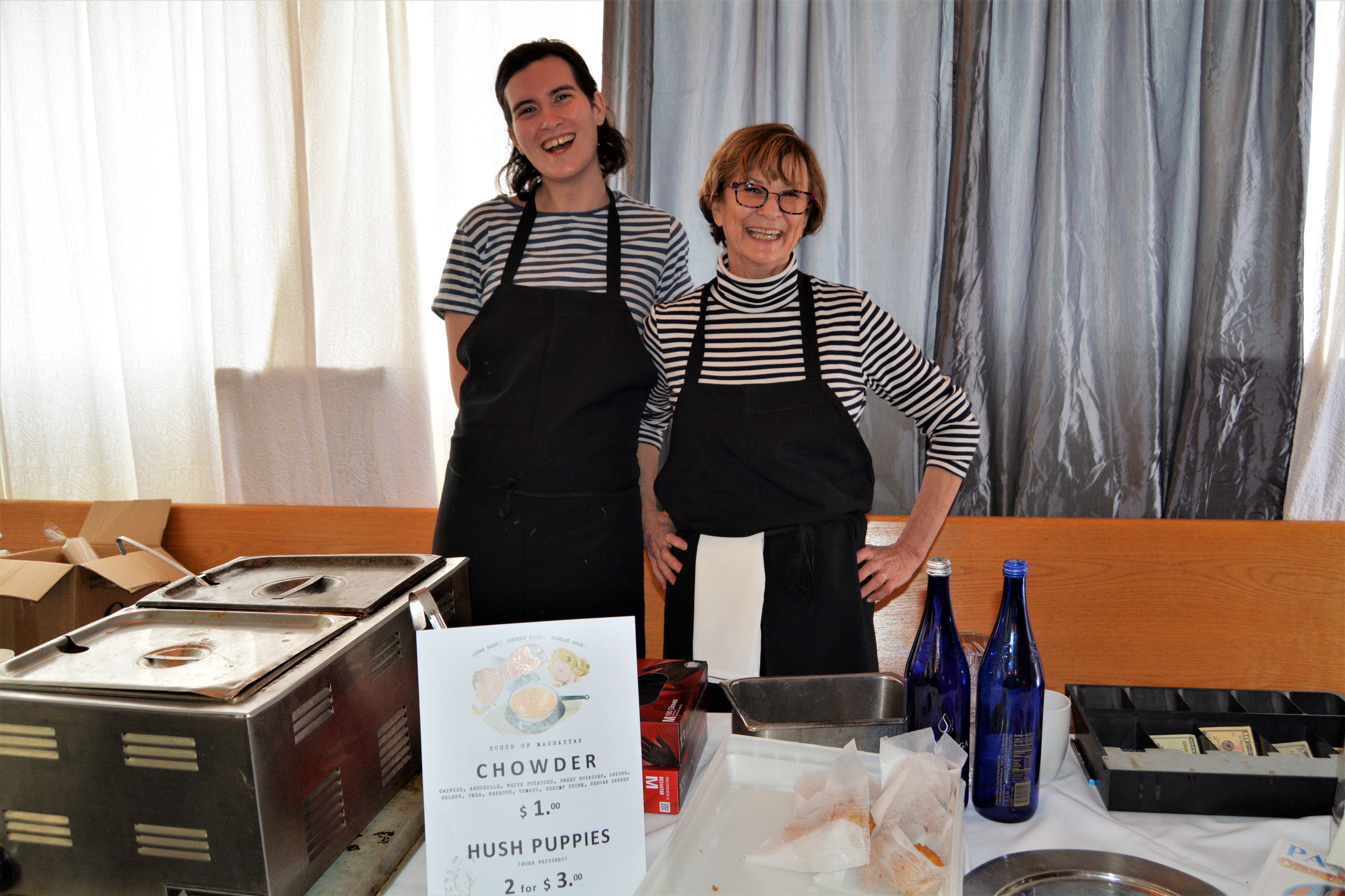 Two servers standing behind chowder at Mouzon