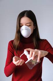Woman wearing facemask applying hand sanitizer