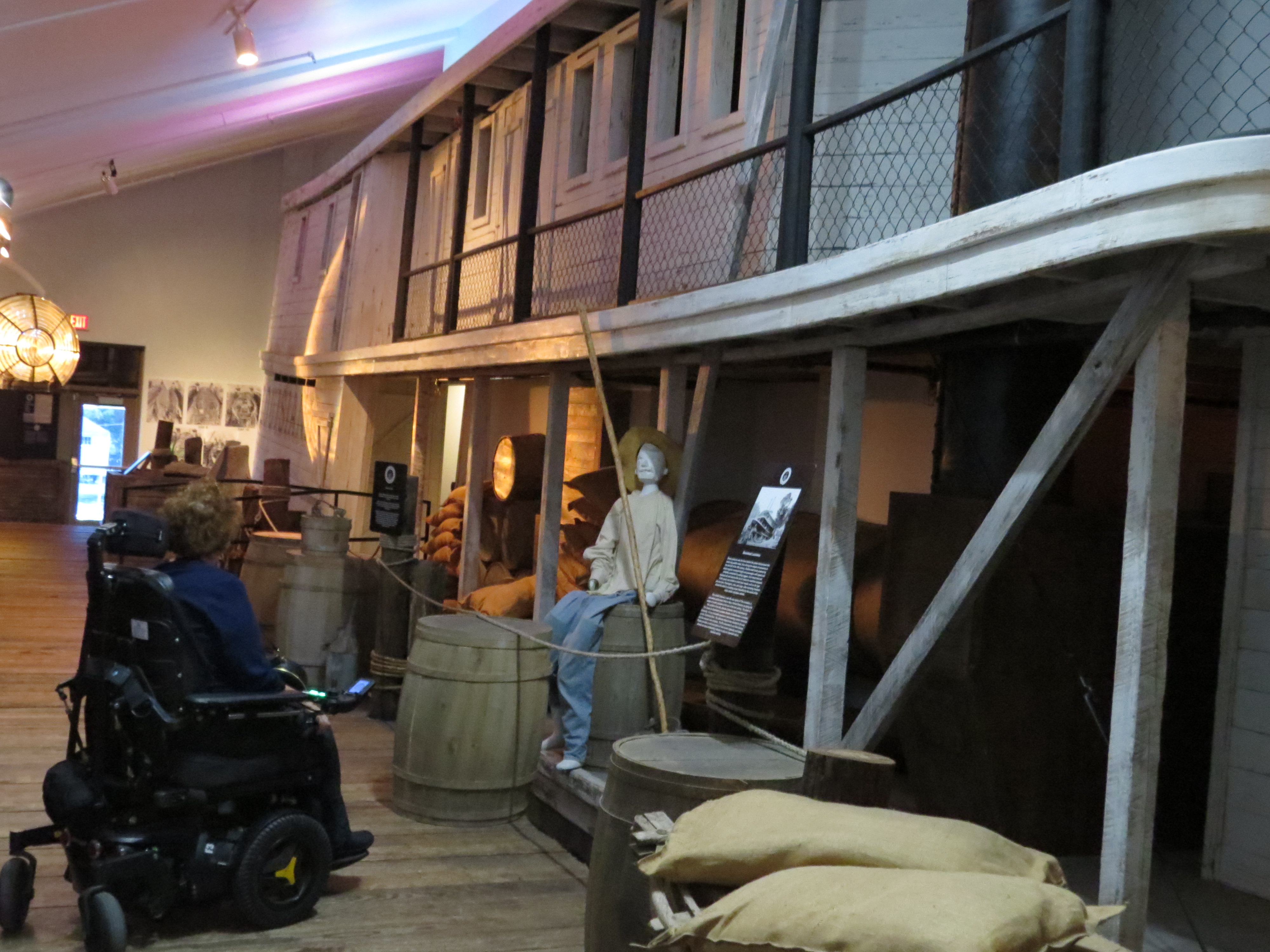 A women in a wheelchair viewing an exhibit at the Lake Pontchartrain Basin Maritime Museum