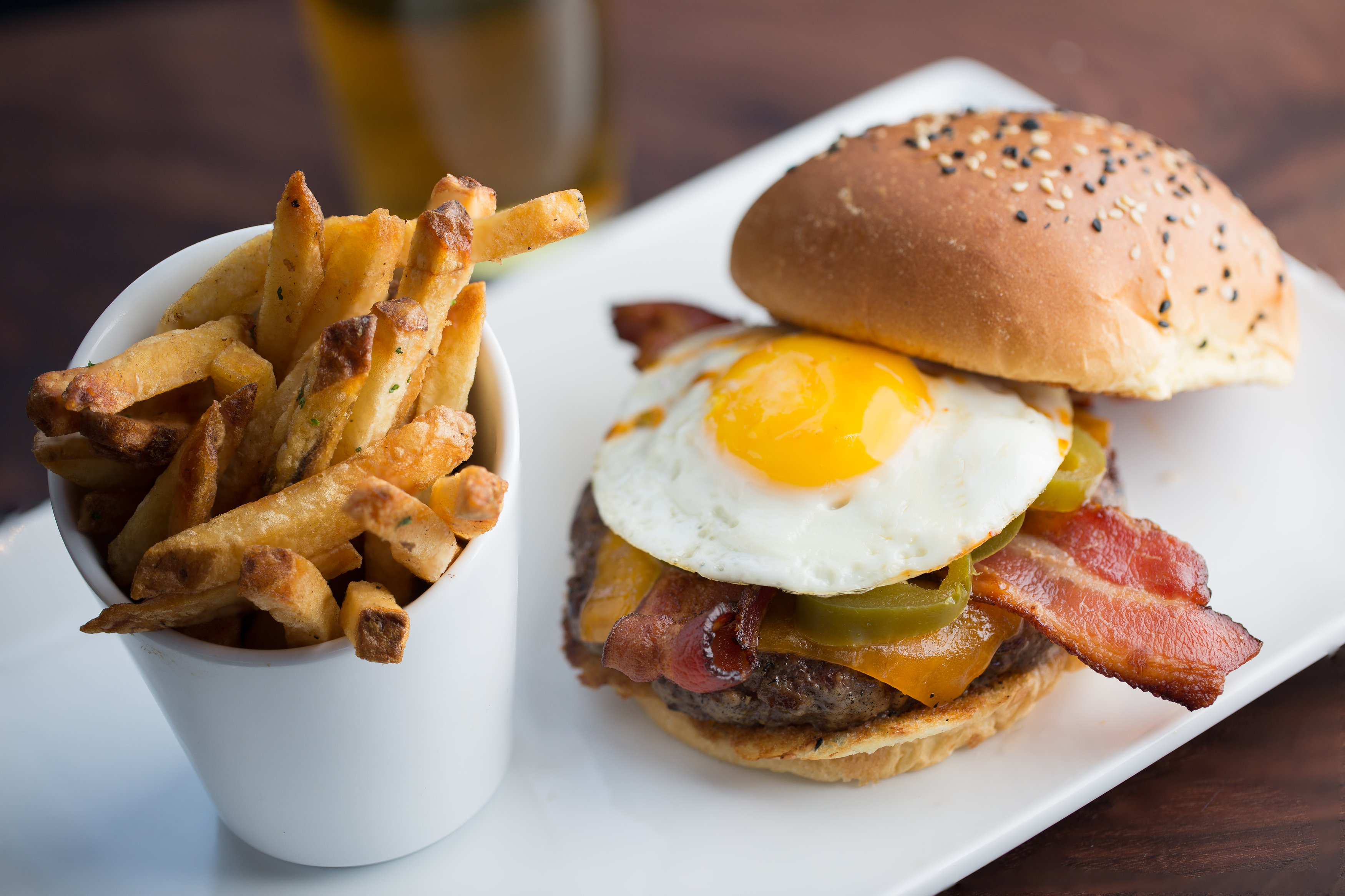 Burger with fried egg and bacon and a side of fries at Eureka! in Huntington Beach