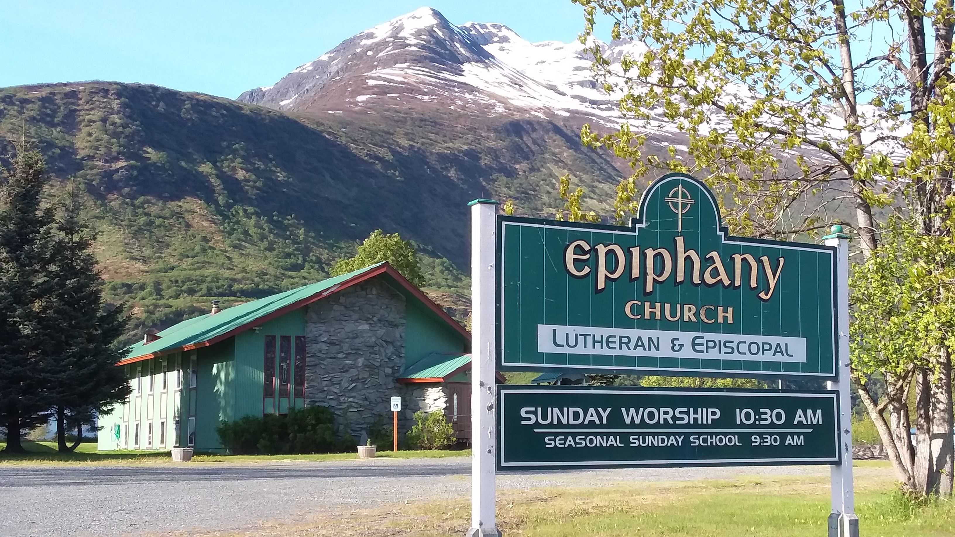 a green church next to a mountain