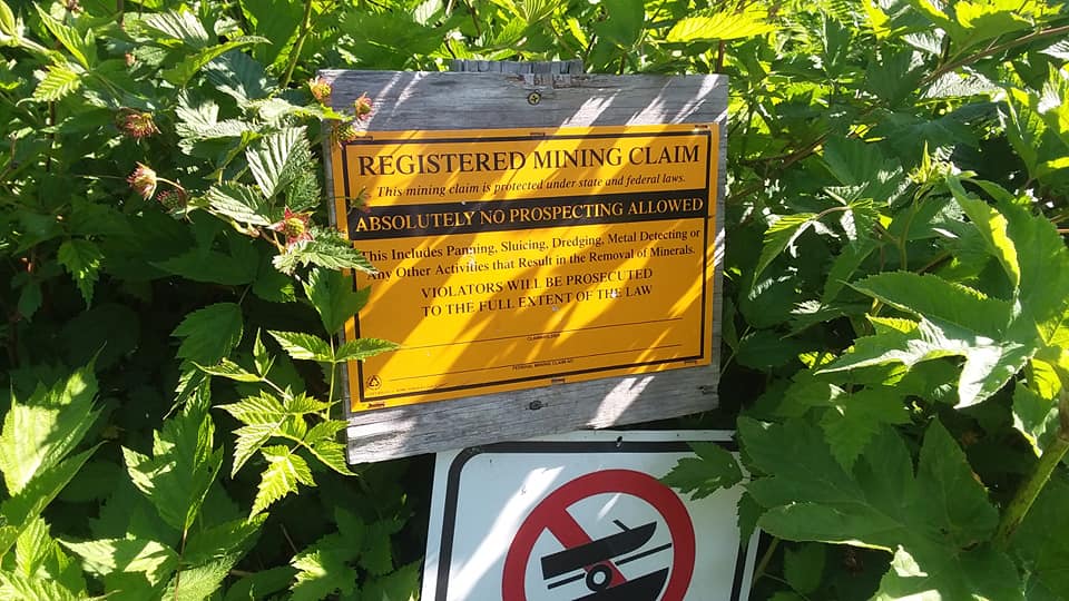 a sign stating "REGISTERED MINING CLAIM" along a hiking trail