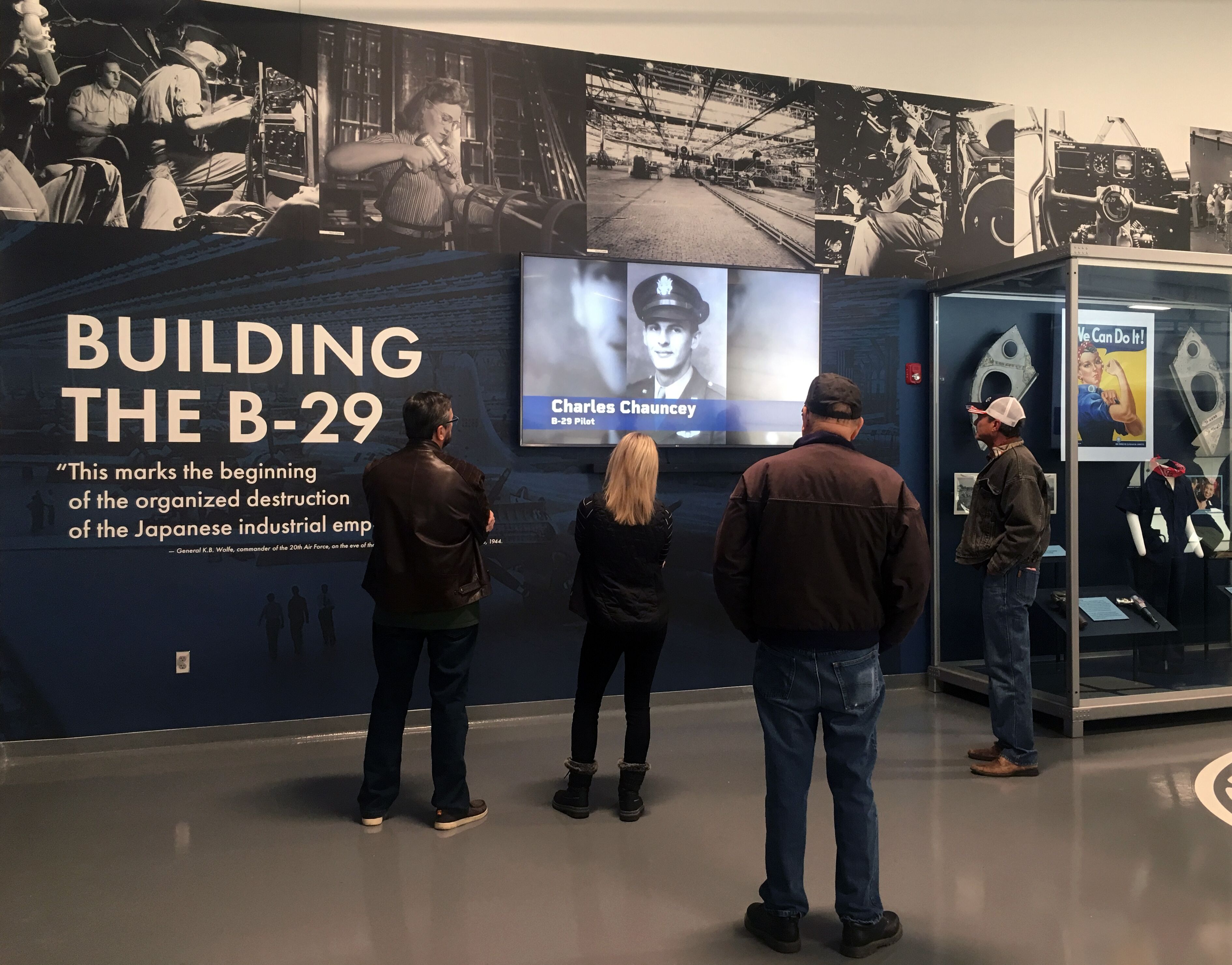 A group of people in the Mezzanine Museum at Doc's hangar watch a video about the B-29's history