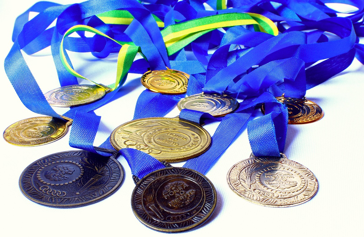 About ten marathon medals with blue ribbons sit in a pile