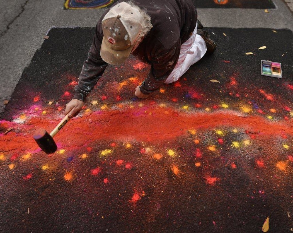 Image of artist creating work on street, bright fall colors