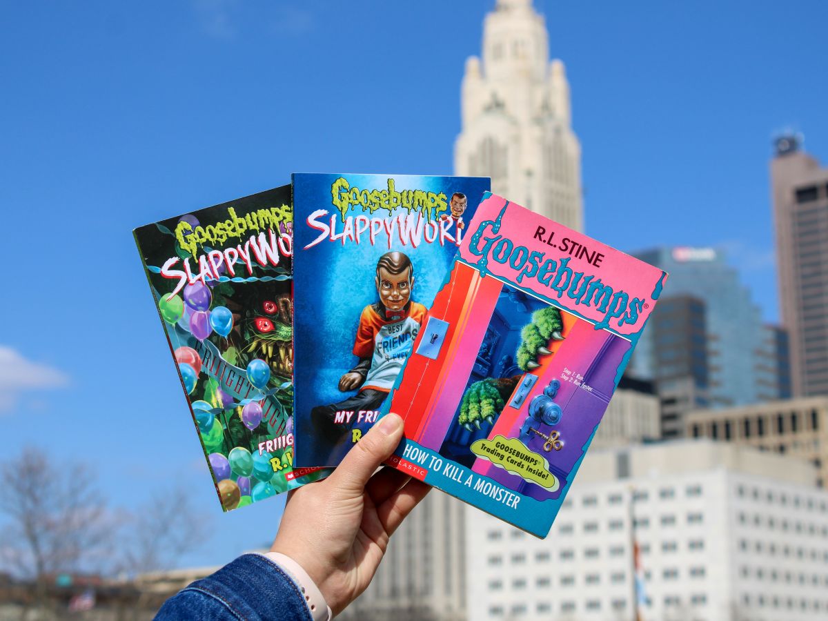 Three Goosebumps books held up against a Columbus skyline