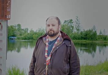 NVE President Aaron Leggett stands next to the Indigenous Place Names marker for Chanshtnu, at Westchester Lagoon.