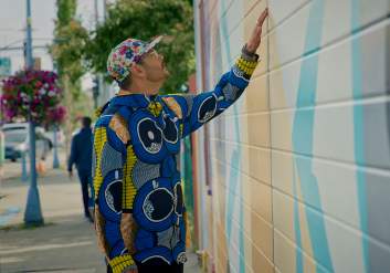 Artist Drew Michael looks at his mural on the side of the Kobuk.