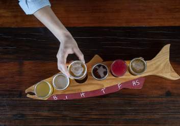 a flight of beers on a salmon-shaped board at an Anchorage brewery.