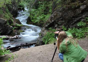 A woman snaps a photo of McHugh Creek on a photo tour throughout Anchorage.