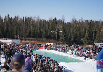 A skier in costume, floats across an icy pond at Hilltop Ski Area's Skim Sink or Swim in spring.