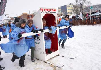Competitors in the Fur Rondy outhouses races push their craft to the finish line on Fourth Avenue.