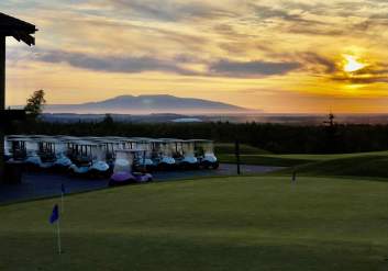Golf carts are lined up at the Anchorage Golf Course as the evening summer sun glides over Mount Susitna.